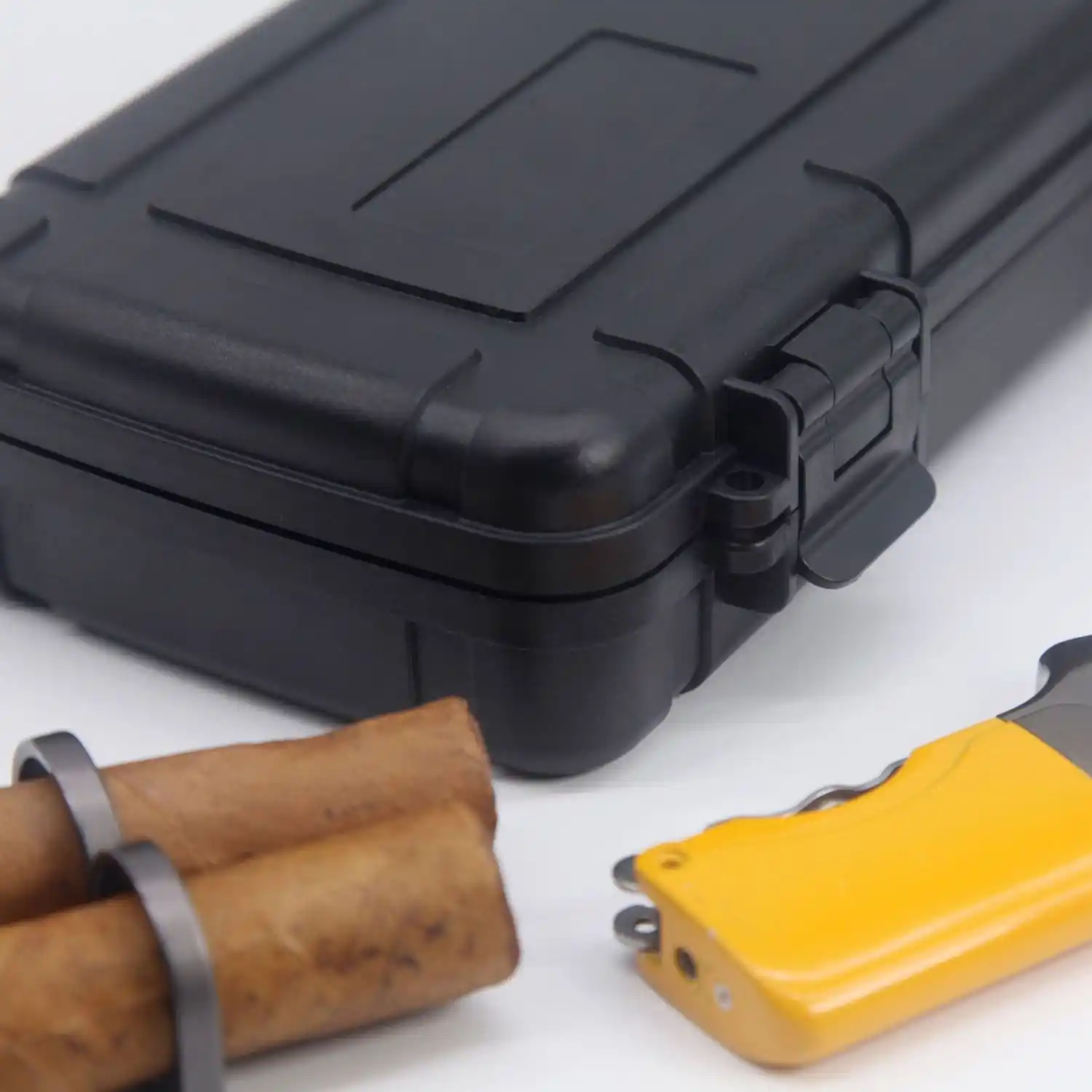 SE1 Rugged Travel Cigar Case – 5‑Cigar ABS | ProTravelHumidors 5 ProTravelHumidors closed black hard‑shell travel cigar humidor with two cigars and a yellow multi‑tool pocket knife blurred in foreground on white surface
